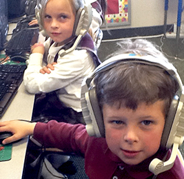 Two students wearing headphones as they use computers