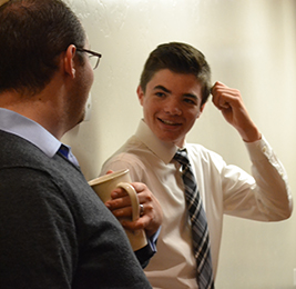 Student talks to a staff member holding a coffee mug