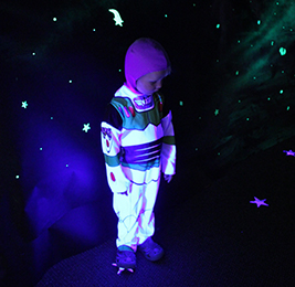Student dressed as Buzz Lightyear poses in glow in the dark room
